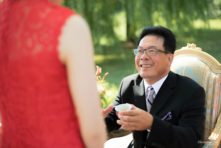 Christopher Luk 2015 - Vannessa and Daniel's Brampton Summer Outdoor Backyard Tea Ceremony Family Wedding Engagement Party Celebration - Bride Groom Navy Blue Suit Asian Red Dress Tea Ceremony Smile Laugh Candid Photojournalistic Father Daughter in Law Cup