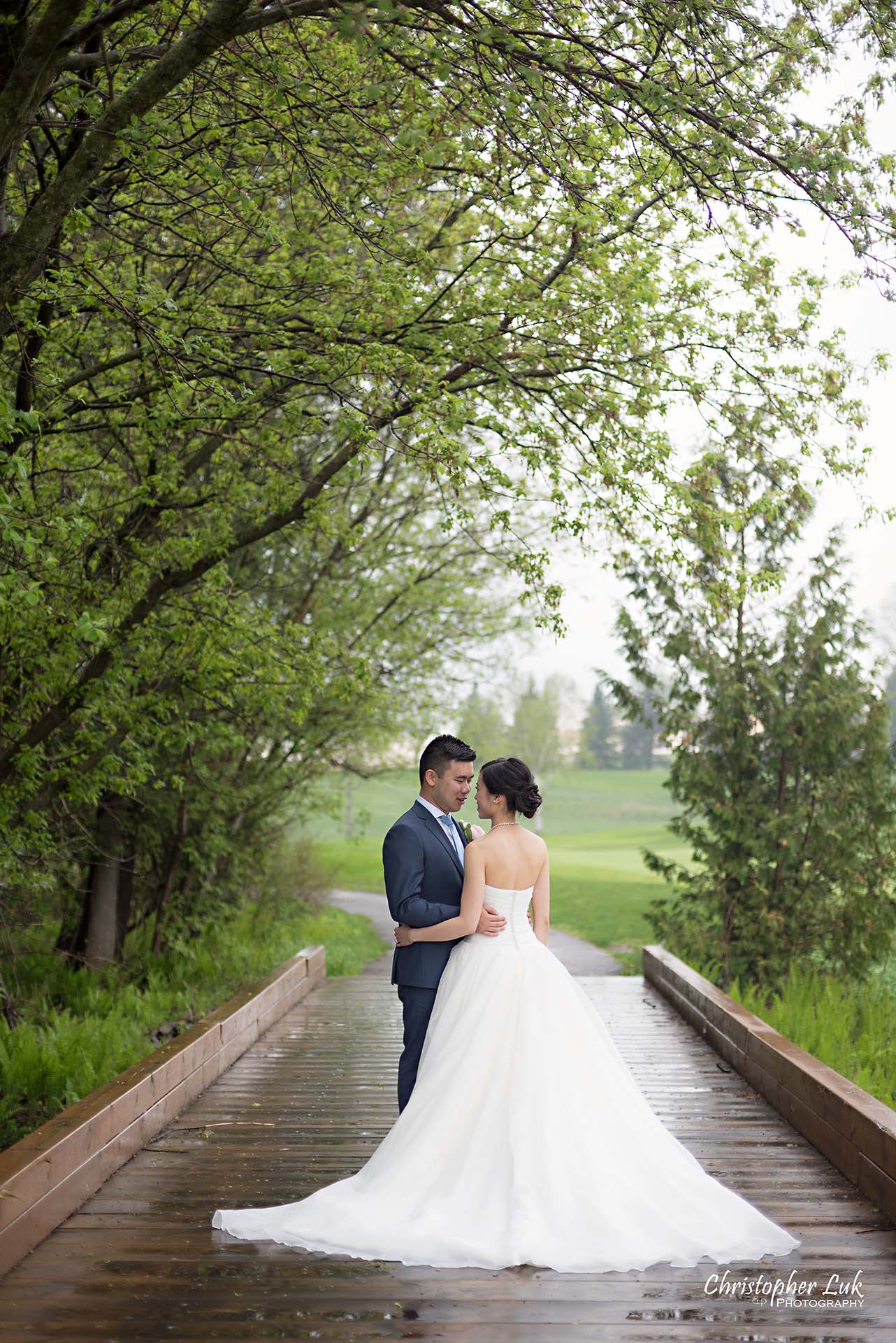 Christopher Luk Toronto Wedding Photographer Angus Glen Golf Club Markham Great Hall Dinner Reception Event Venue Green Field Sunset Bride Groom Natural Candid Photojournalistic Wooden Bridge Green Arch Trees Holding Each Other Hug Bridal Dress Gown Train Portrait 