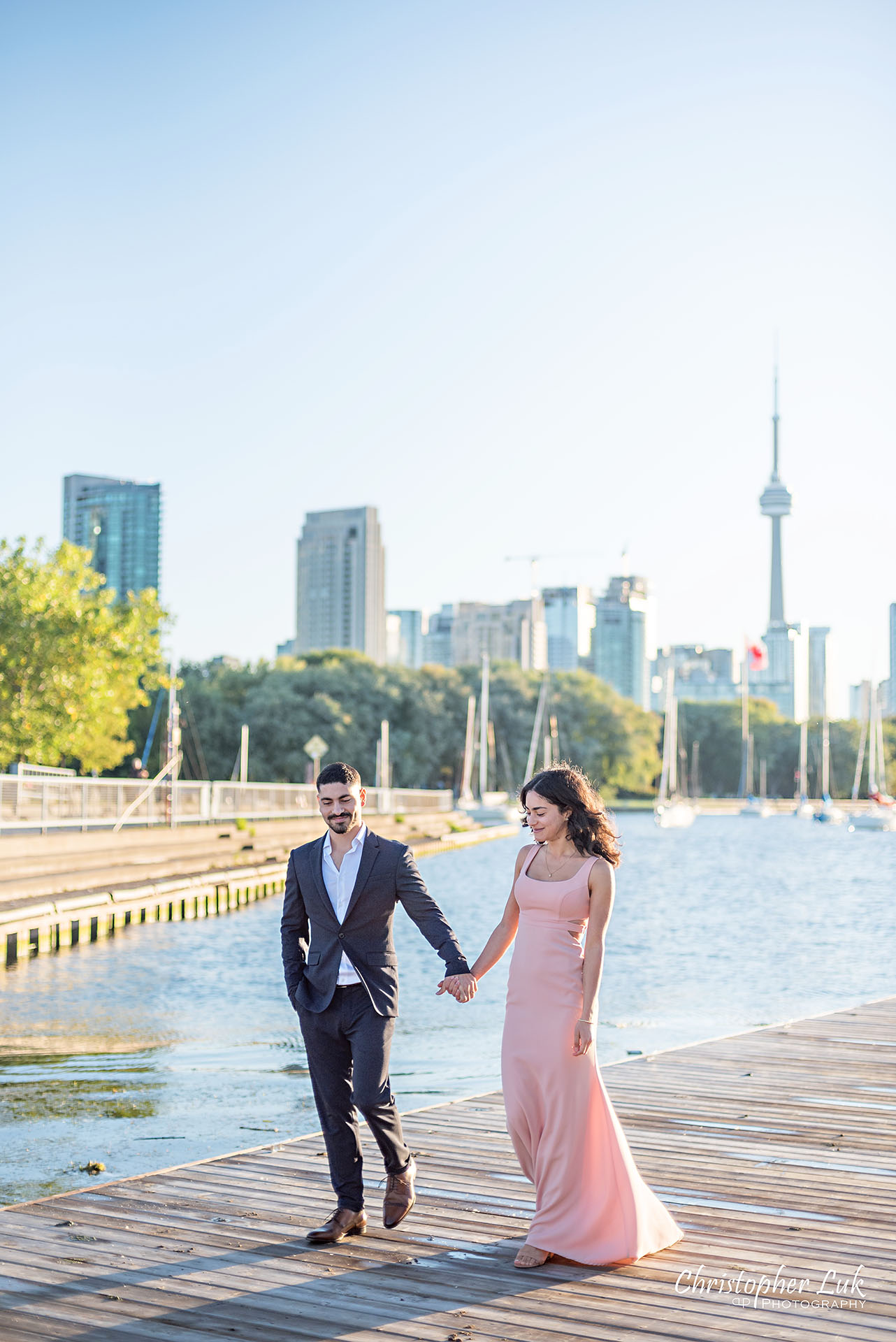 Christopher Luk Trillium Park Ontario Place Waterfront Engagement Session Toronto Wedding Photographer Bride Groom Natural Candid Photojournalistic Boat Dock CN Tower Skyline Background Sunrise Kiss Vertical Portrait Hotel X