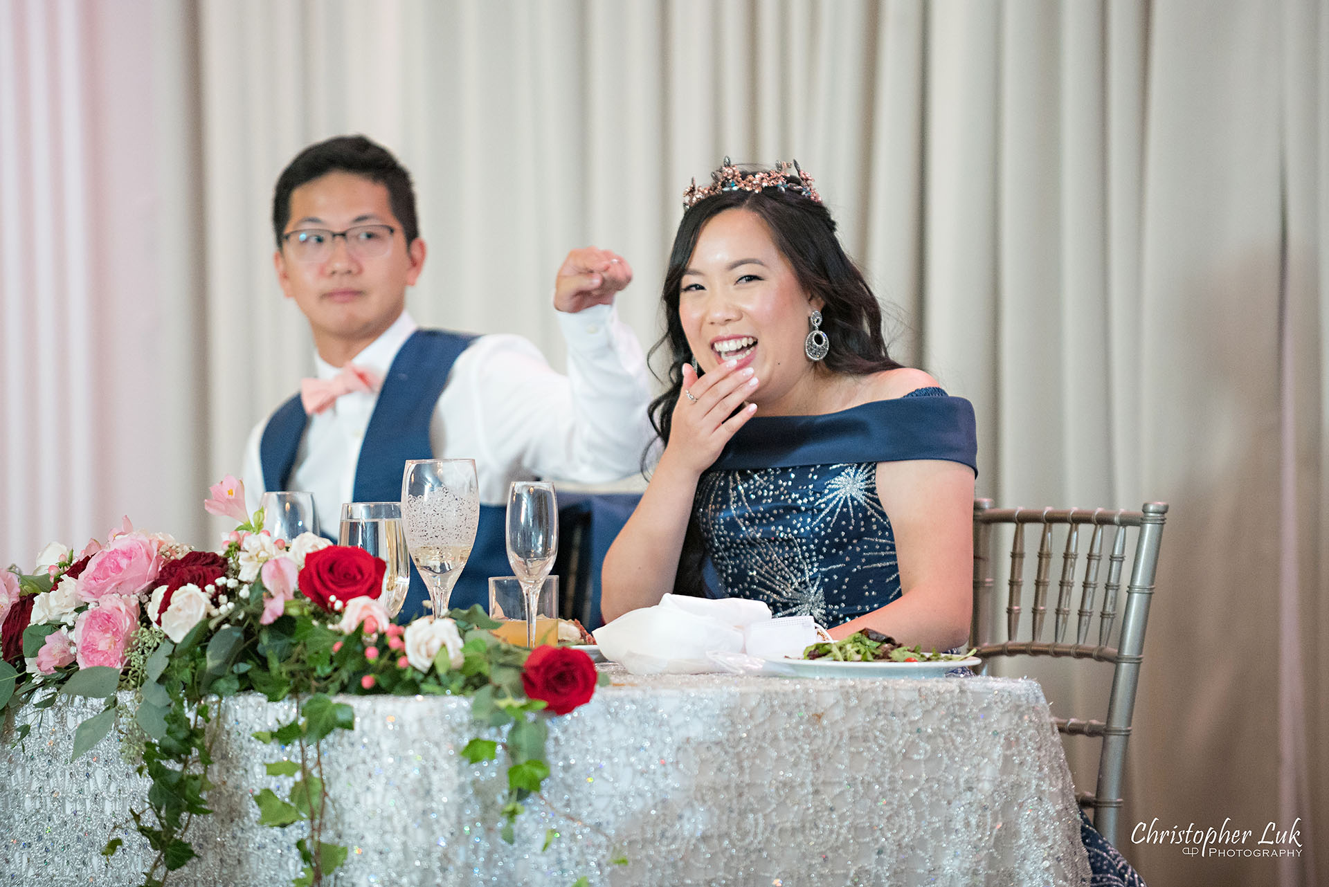 Christopher Luk Toronto Wedding Photographer Bridle Trail Baptist Church Unionville Main Street Crystal Fountain Event Venue Head Table Decor Flower Bell by Masami Crystal Linen Setup Wide Stage Curtains Bride Groom Speeches Laugh Reaction Pointing Funny