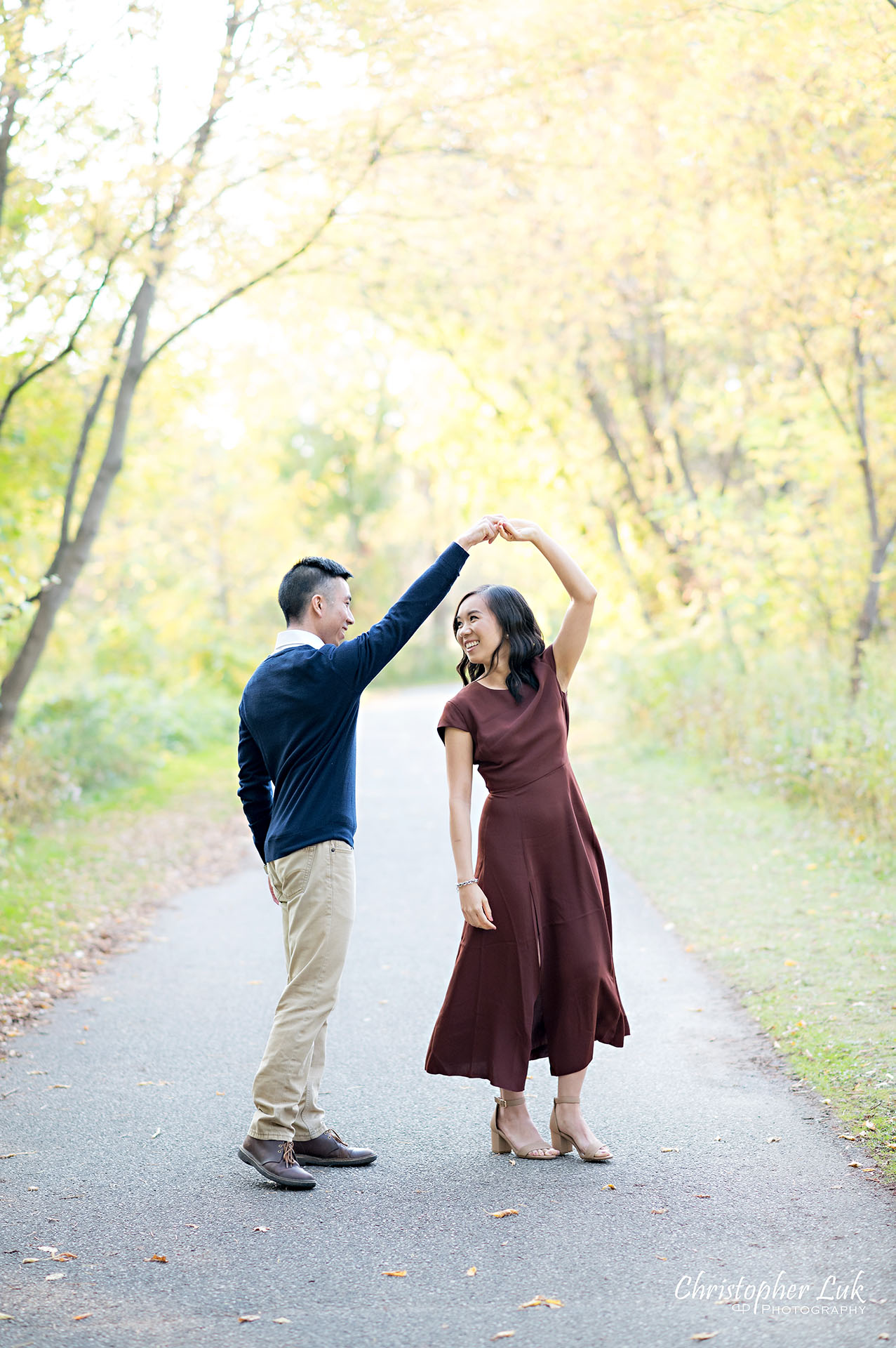 Christopher Luk Toronto Wedding Engagement Session Photographer Autumn Fall Leaves Natural Candid Photojournalistic Bride Groom Holding Hands Walking Together Pathway Hiking Trail Dancing Twirl Spin