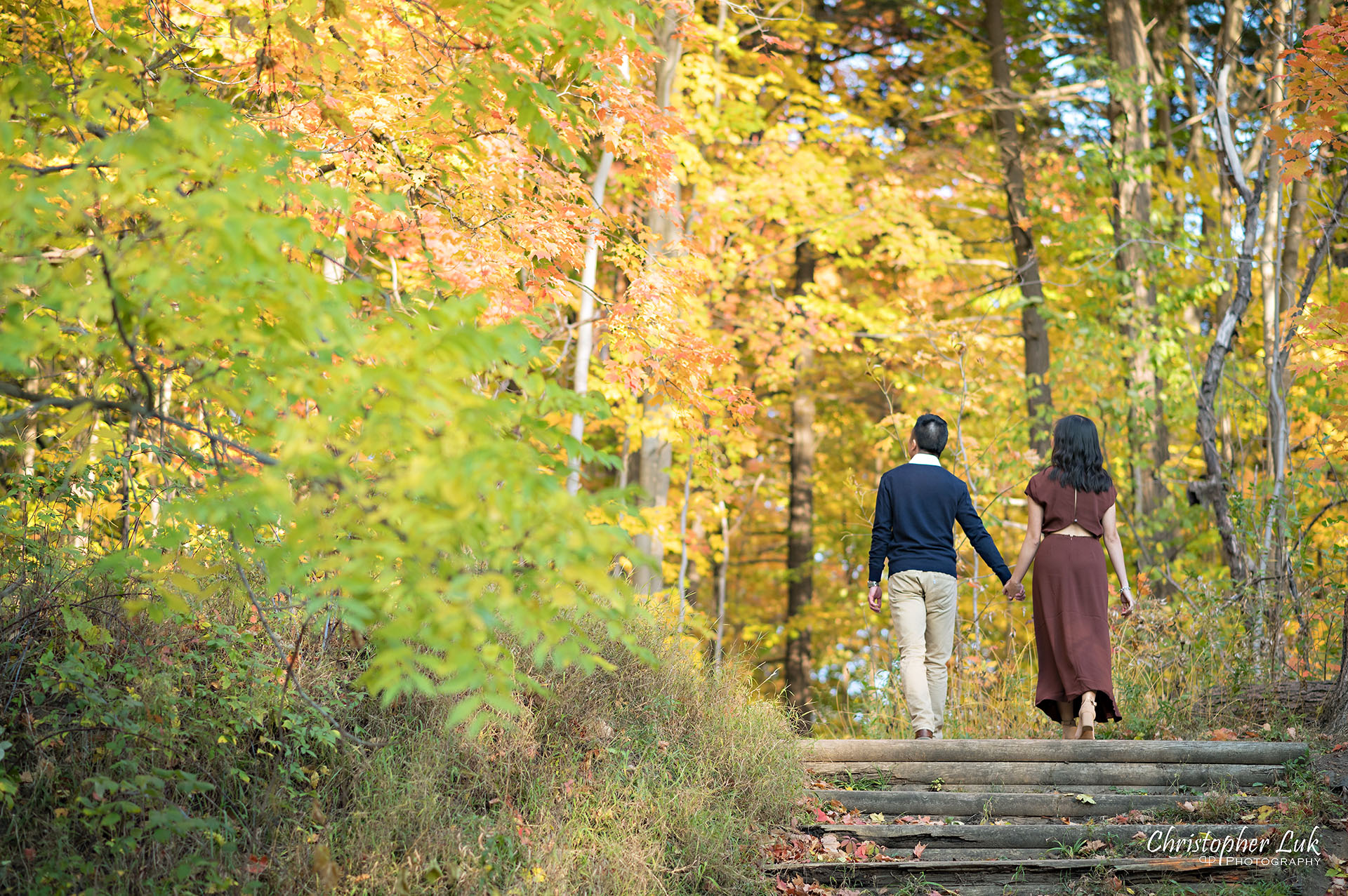 Christopher Luk Toronto Wedding Engagement Session Photographer Autumn Fall Leaves Natural Candid Photojournalistic Bride Groom Hiking Trail Trees Hug Holding Each Other Together Orange Red Yellow Kiss Wood Wooden Stairs Staircase Hiking Trail Steps