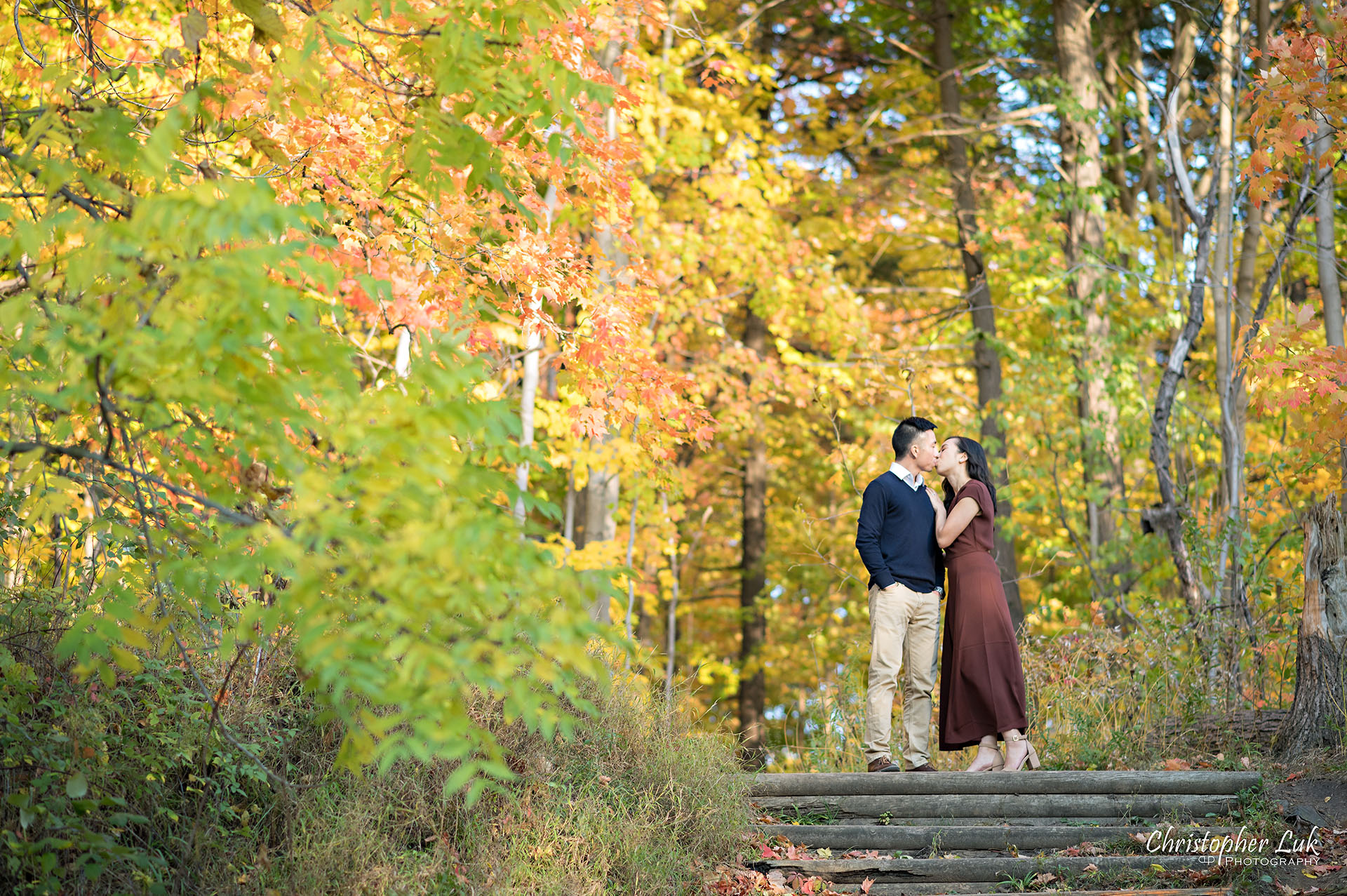 Christopher Luk Toronto Wedding Engagement Session Photographer Autumn Fall Leaves Natural Candid Photojournalistic Bride Groom Hiking Trail Trees Hug Holding Each Other Together Orange Red Yellow Kiss Wood Wooden Stairs Staircase Hiking Trail Steps