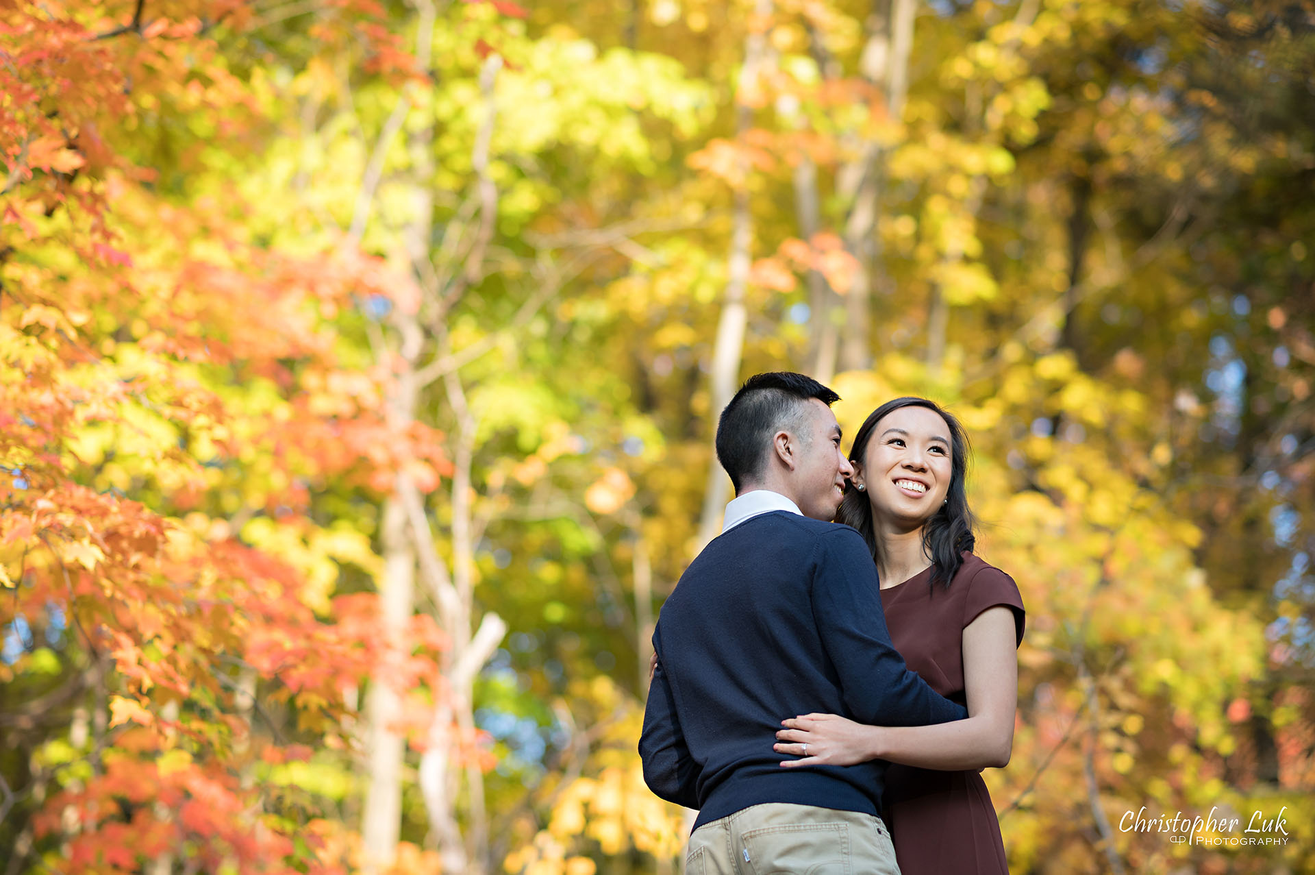 Christopher Luk Toronto Wedding Engagement Session Photographer Autumn Fall Leaves Natural Candid Photojournalistic Bride Groom Hiking Trail Trees Hug Holding Each Other Together Orange Red Yellow