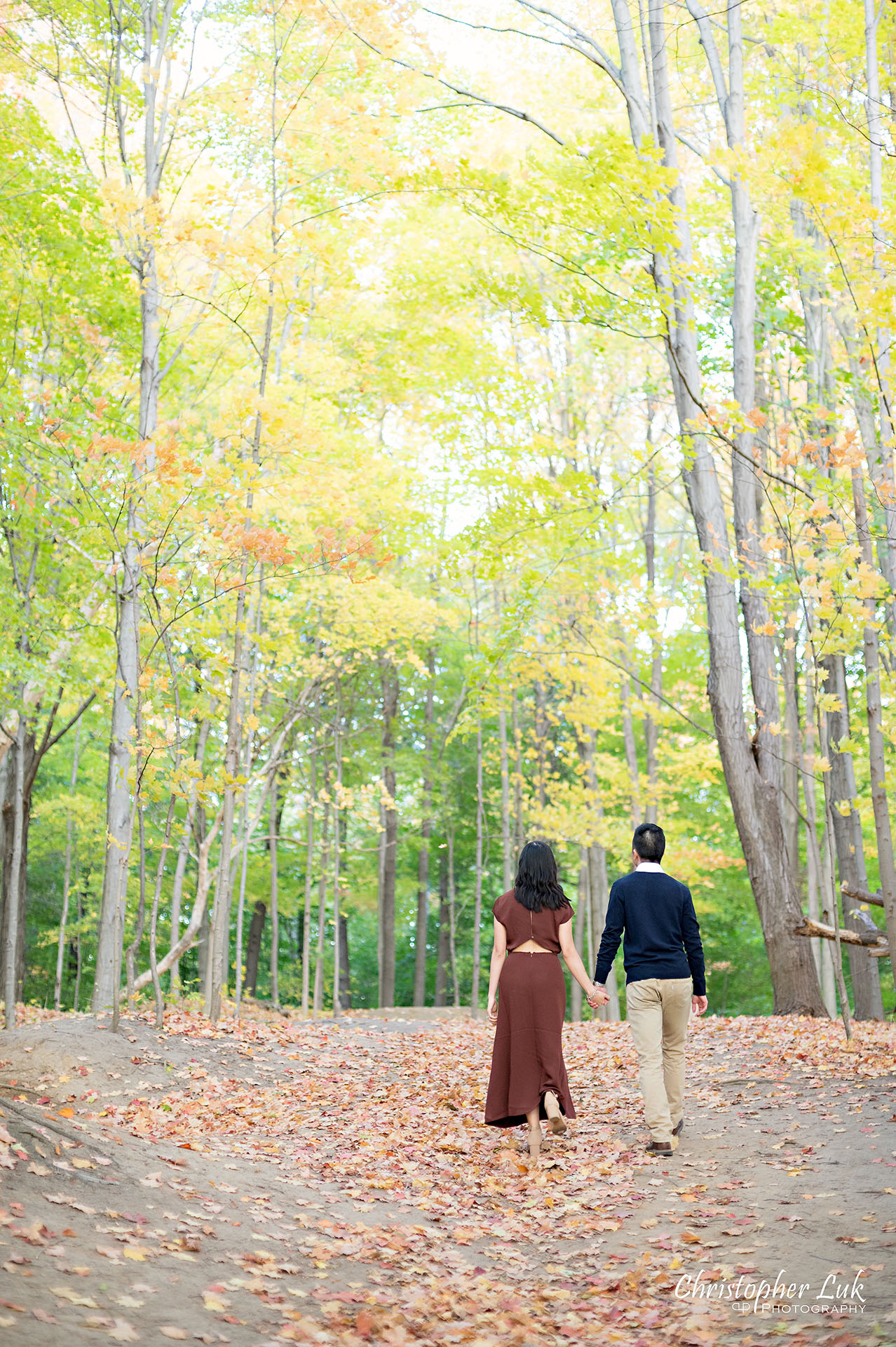 Christopher Luk Toronto Wedding Engagement Session Photographer Autumn Fall Leaves Natural Candid Photojournalistic Bride Groom Hiking Trail Trees Holding Hands Together Walking