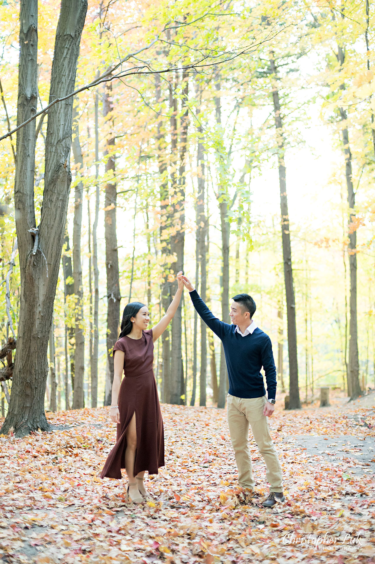 Christopher Luk Toronto Wedding Engagement Session Photographer Autumn Fall Leaves Natural Candid Photojournalistic Bride Groom Holding Hands Walking Together Pathway Hiking Trail Dancing Twirl Spin Trees