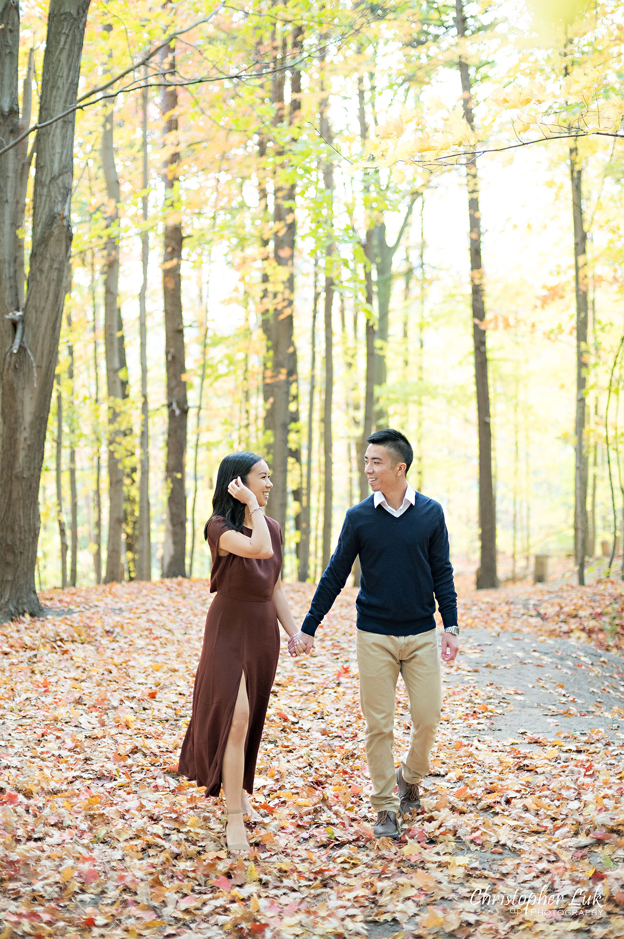 Christopher Luk Toronto Wedding Engagement Session Photographer Autumn Fall Leaves Natural Candid Photojournalistic Bride Groom Hiking Trail Trees Smiling Each Other Happy Walking Holding Hands Together 