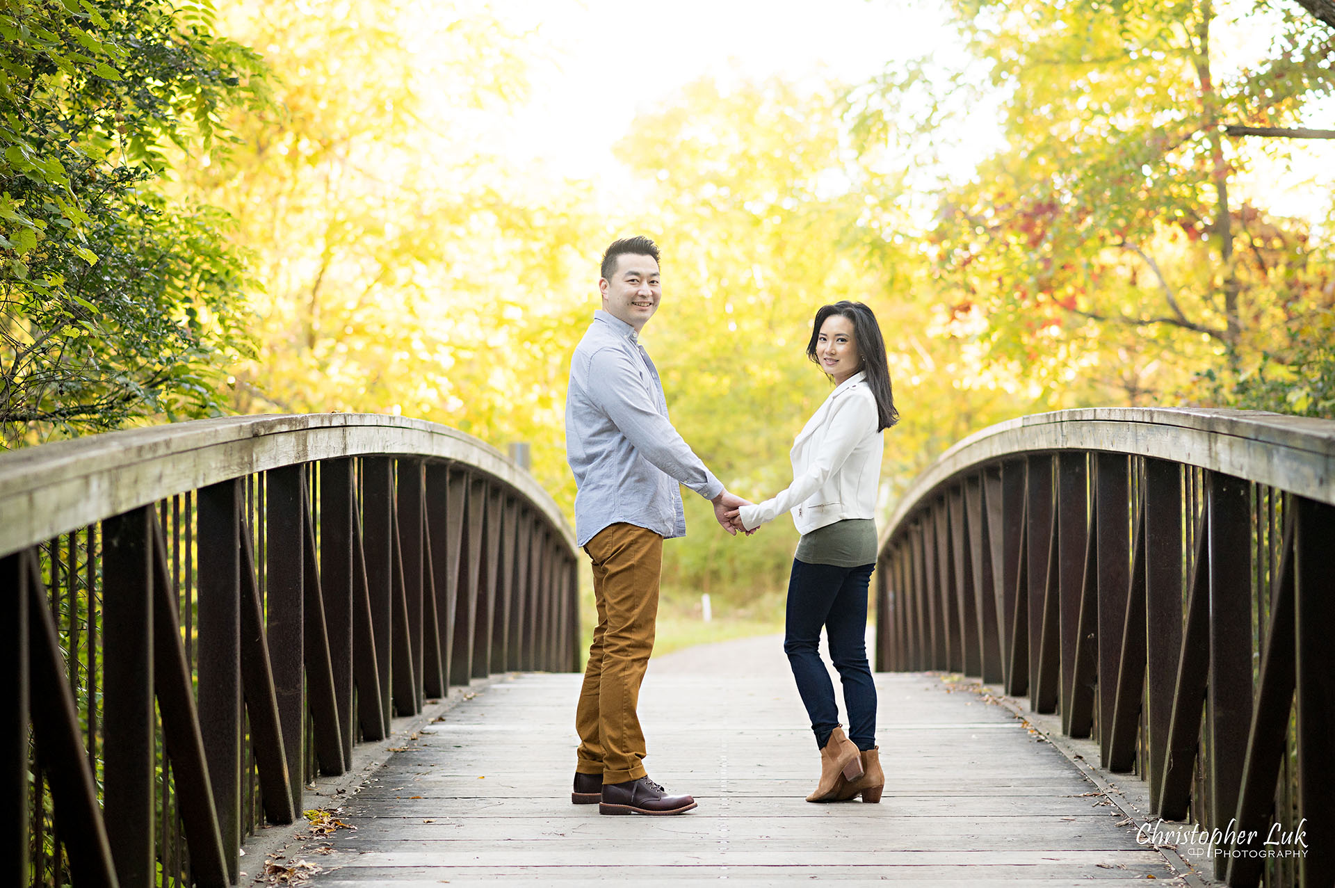Mother Father Husband Wife Holding Hands Walking Together on Bridge Autumn Fall Leaves Markham Unionville Toronto Family Photographer Landscape