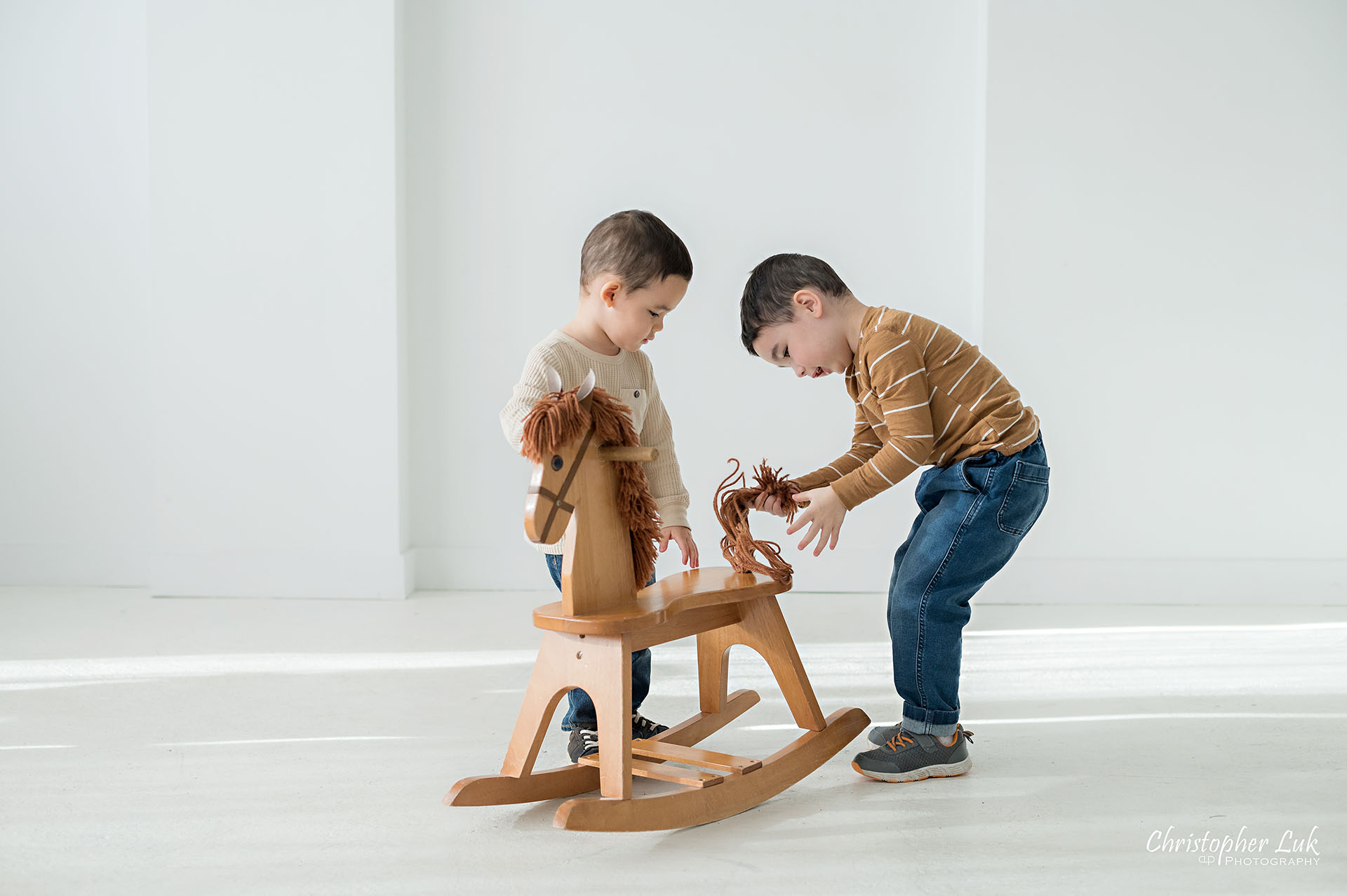 Sons Brothers Toddler Children Playing Together Wooden Rocking Horse Family Studio Portrait Candid Natural Photojournalistic