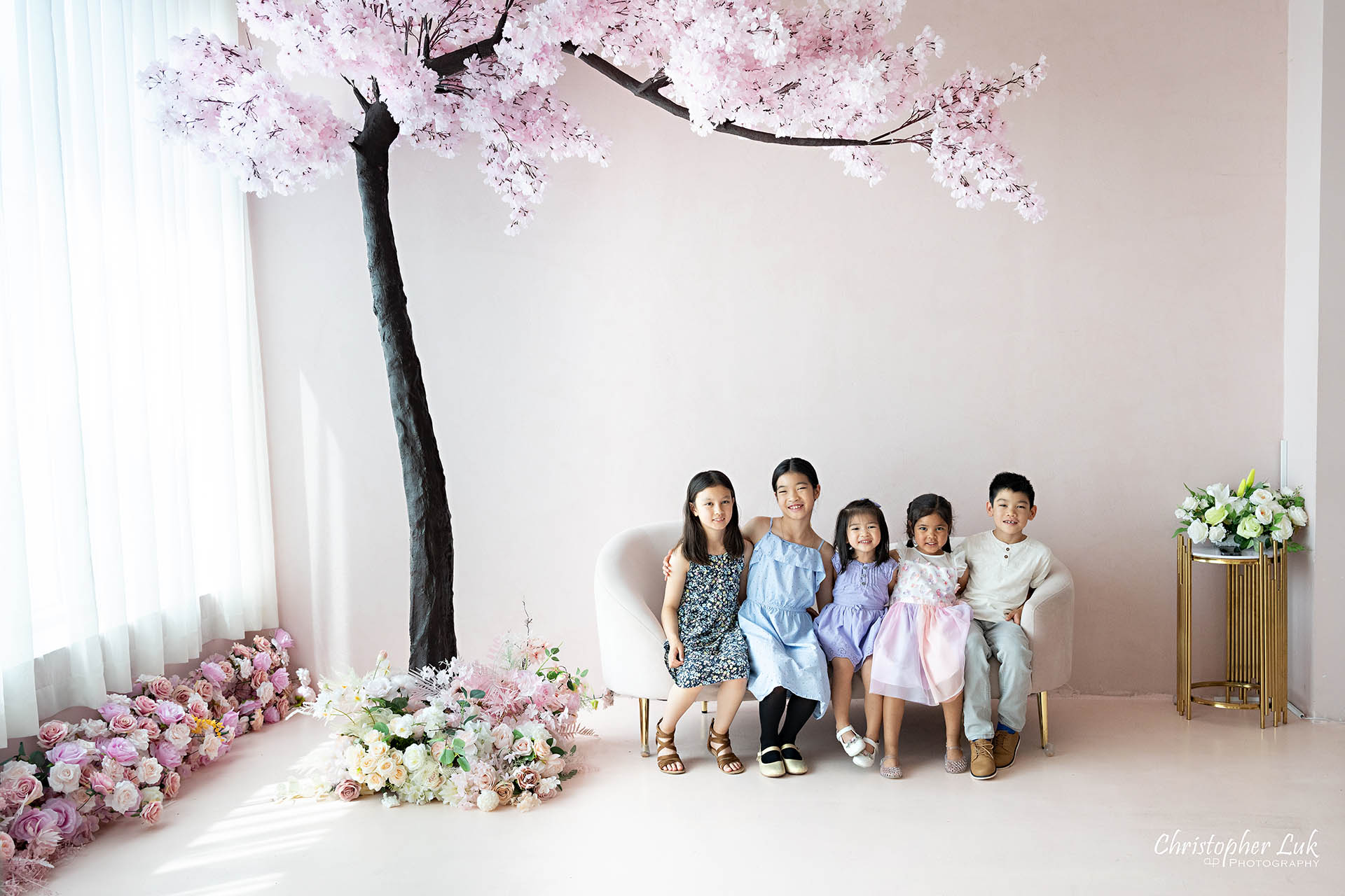 Grandchildren cousins children family photo Toronto natural light photography studio cherry blossoms pink flowers tree cute adorable hug